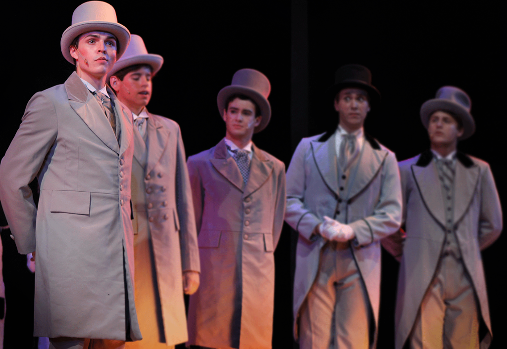 A group of actors all wearing tail coats
