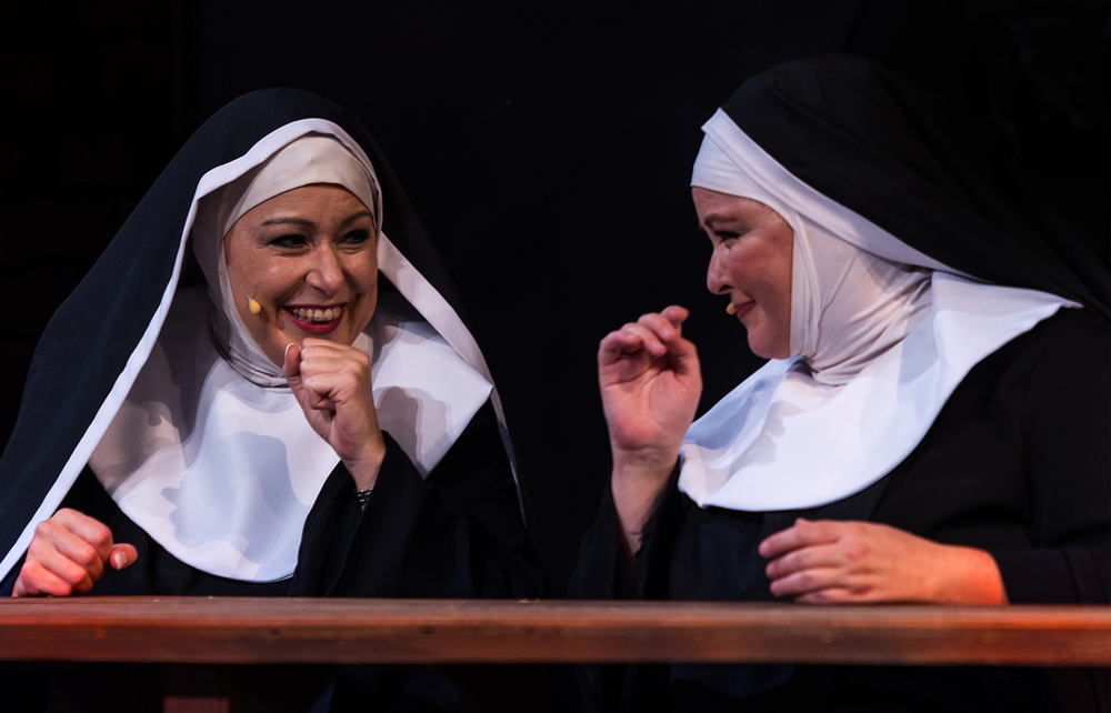 nuns giggling with each other at the dinner table