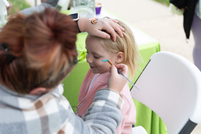A photo of a girl getting her face painted by an artisti