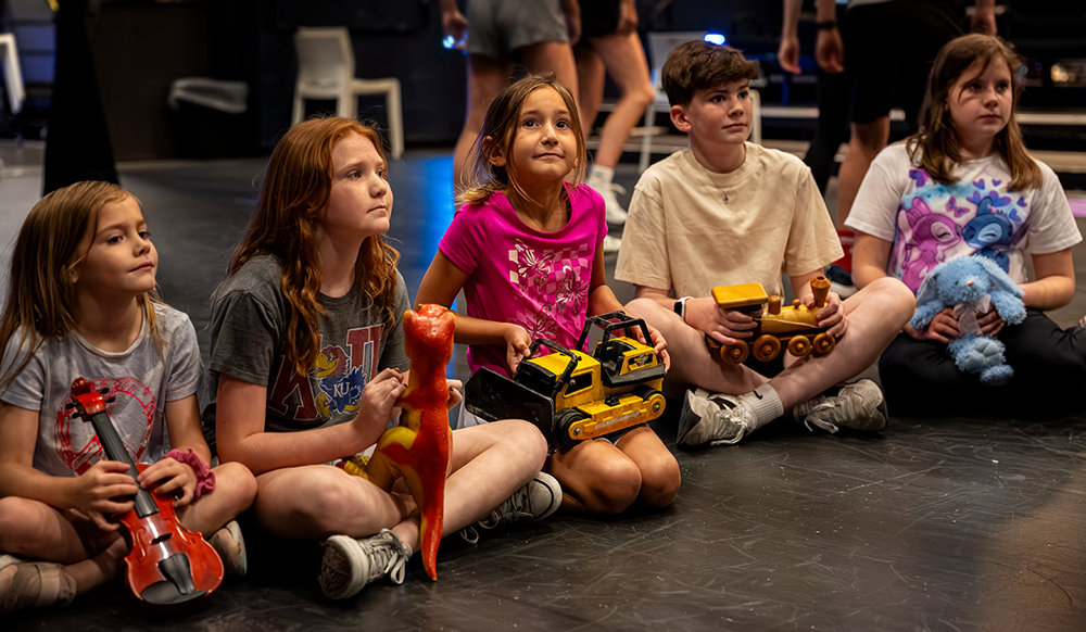 group of kids acting in a scene sitting on the floor